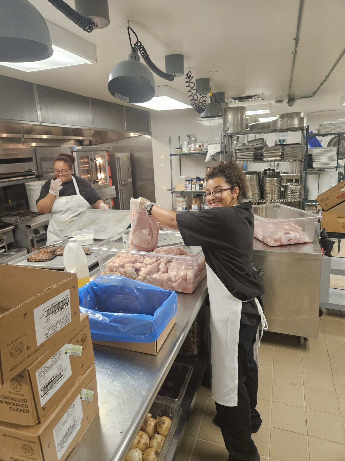 Abigail holding meat while working in the kitchen.