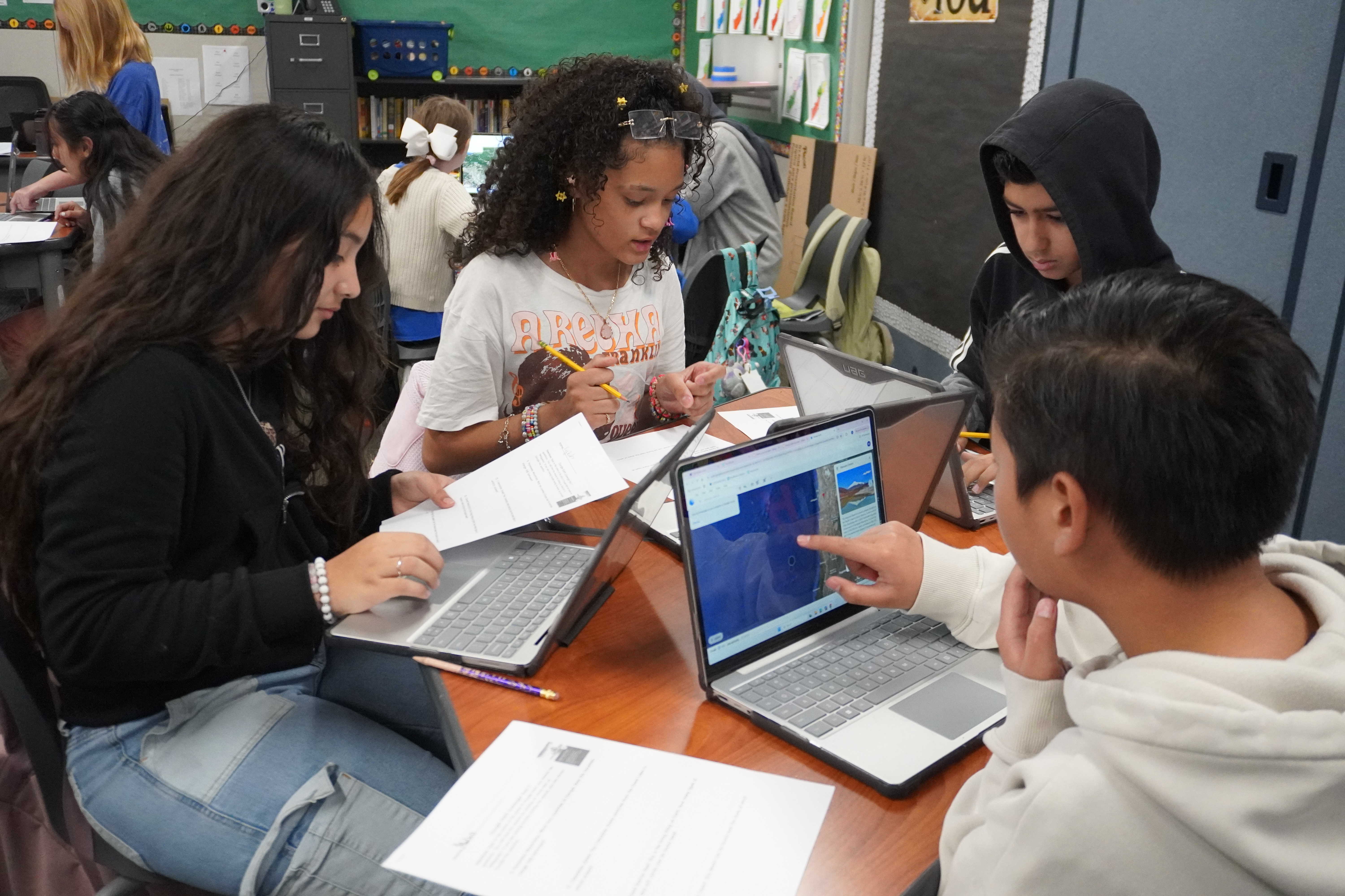 Image of 5th-grade students actively engaging  in classwork on their technology devices, enhancing their learning experience through interactive, hands-on activities.
