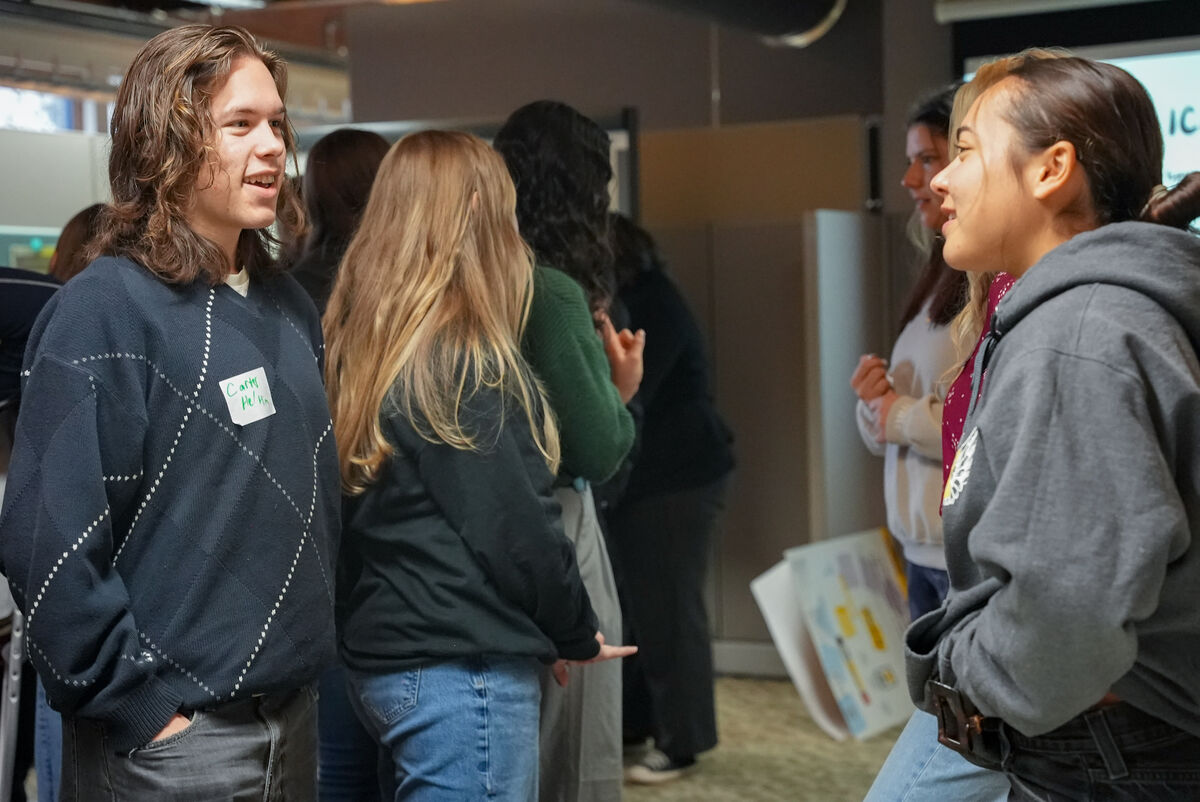 two students talk within a crowd of other students