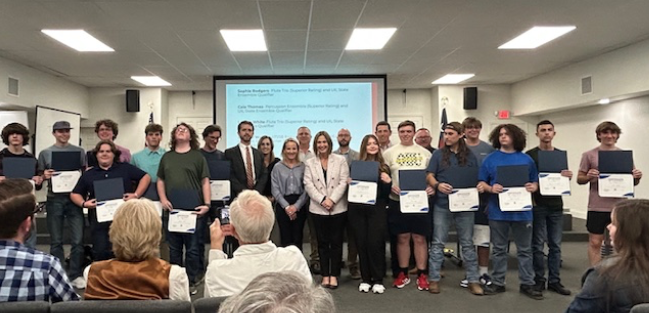 Group of band students with awards standing up with the school board