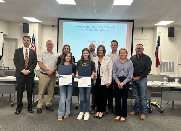 Two girls with awards standing up with the school board