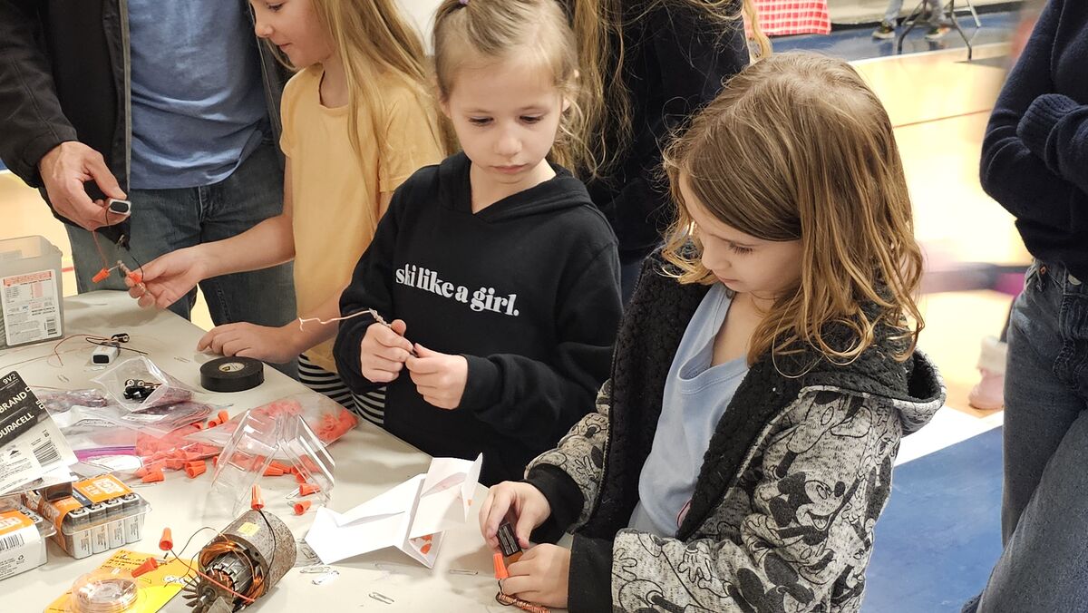 Two young girls work on a science project, focusing intently on their task.