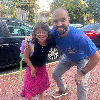 Teacher greeting child in backpack