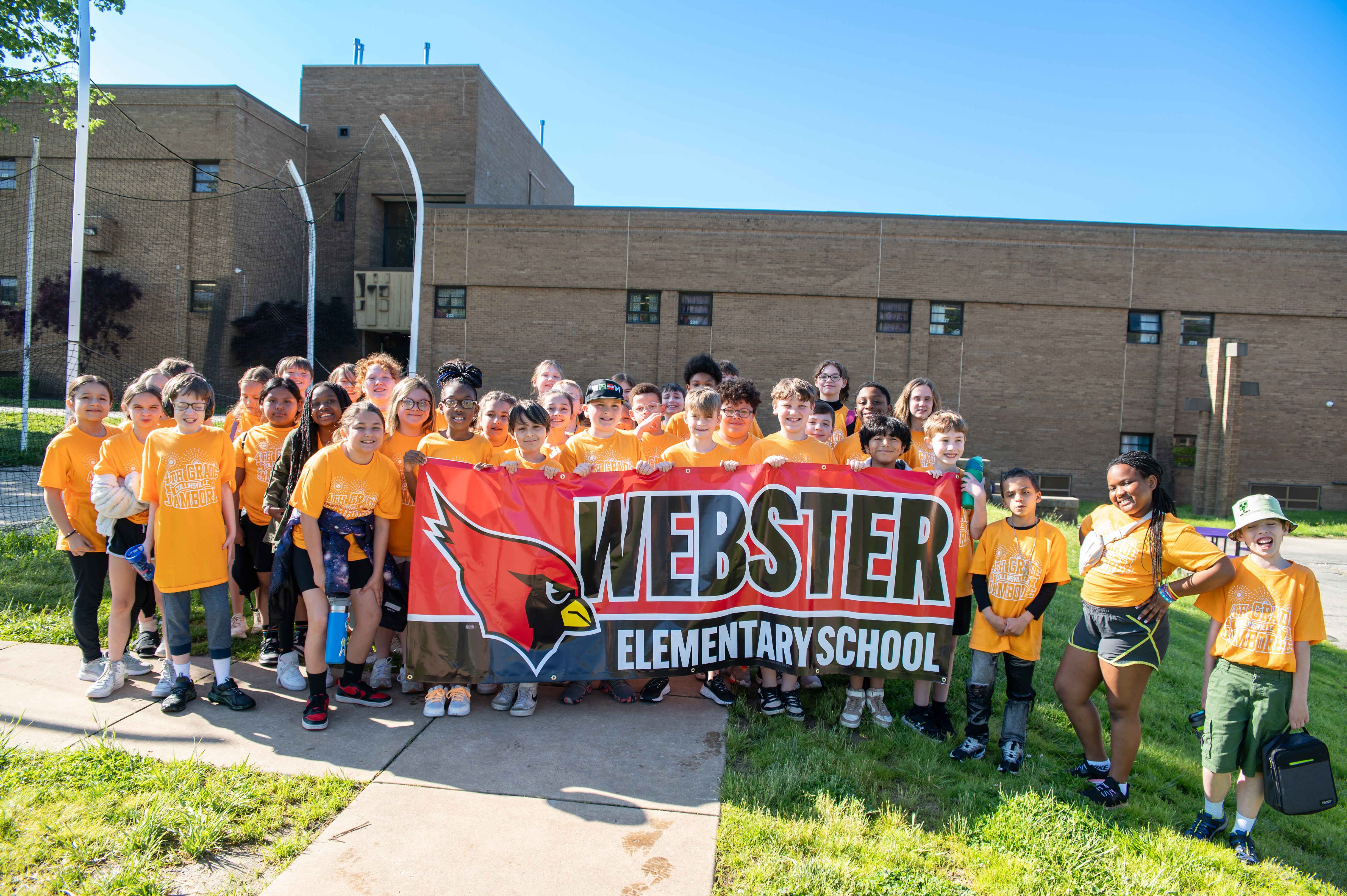 A group of students from Webster Elementary School pose for a photo with a large banner.