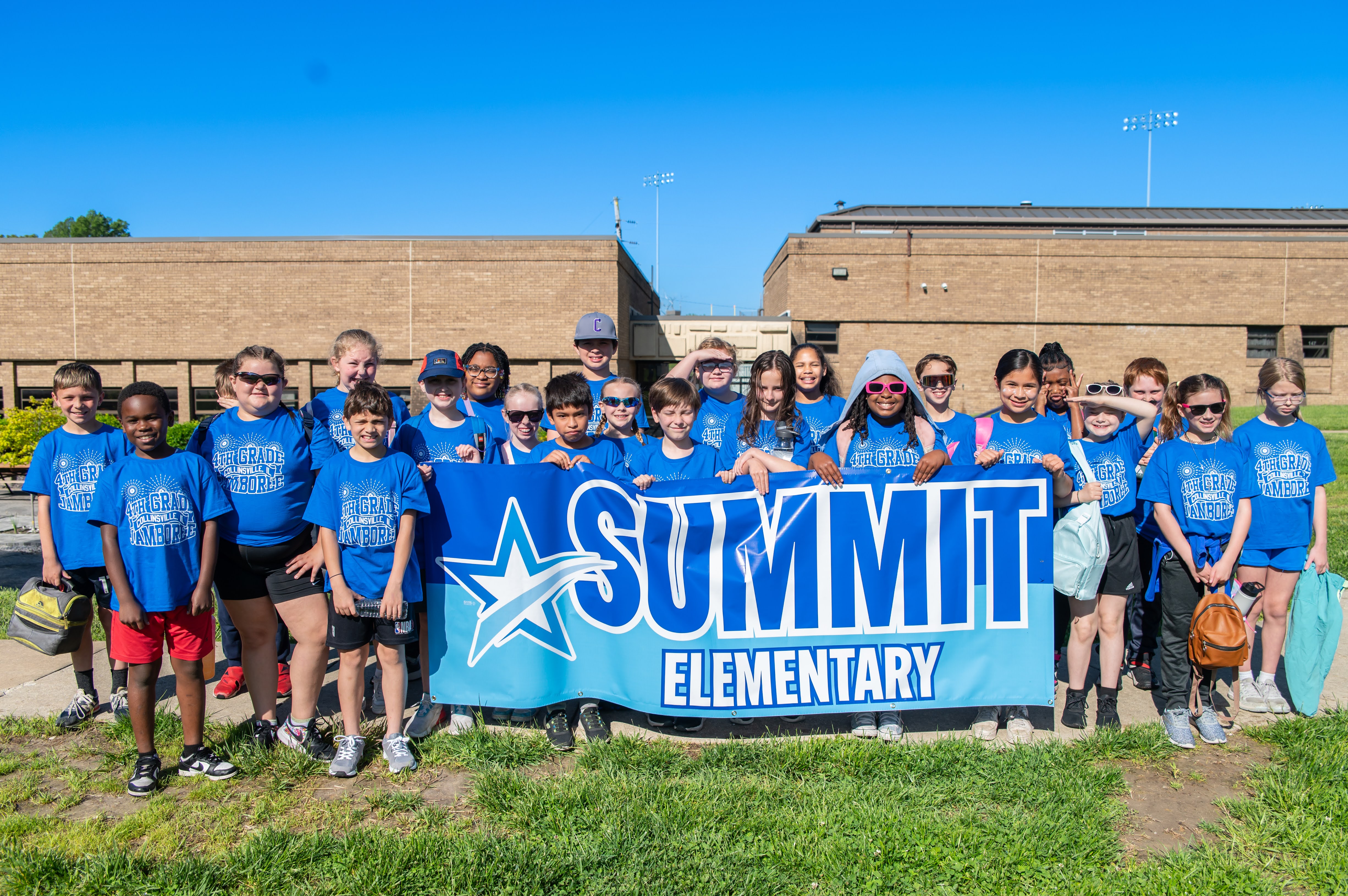 A group of children from Summit Elementary School stand together holding a banner.
