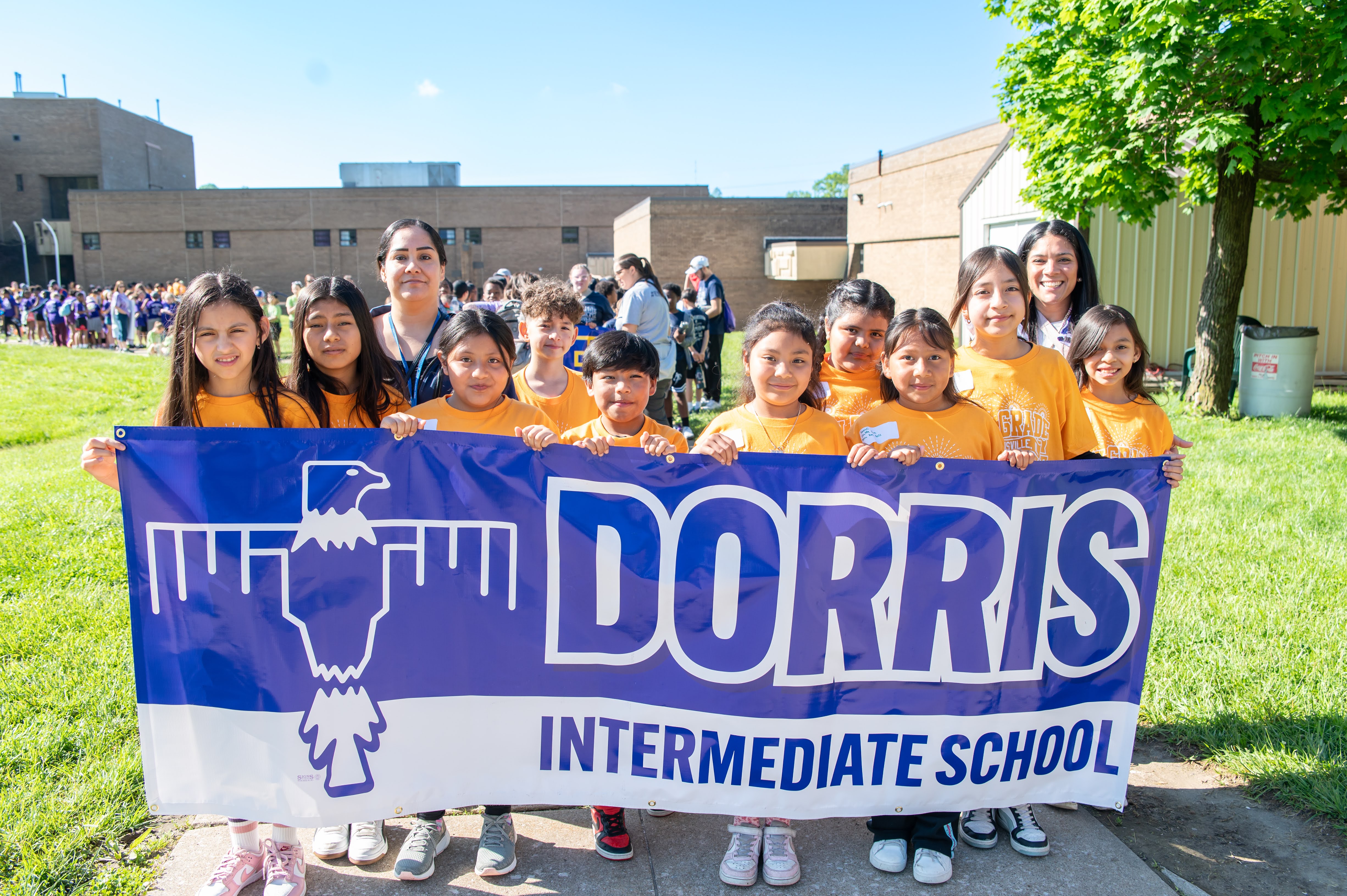 A group of students and a teacher hold a banner that reads 'Dorris Intermediate School' with a stylized eagle design.