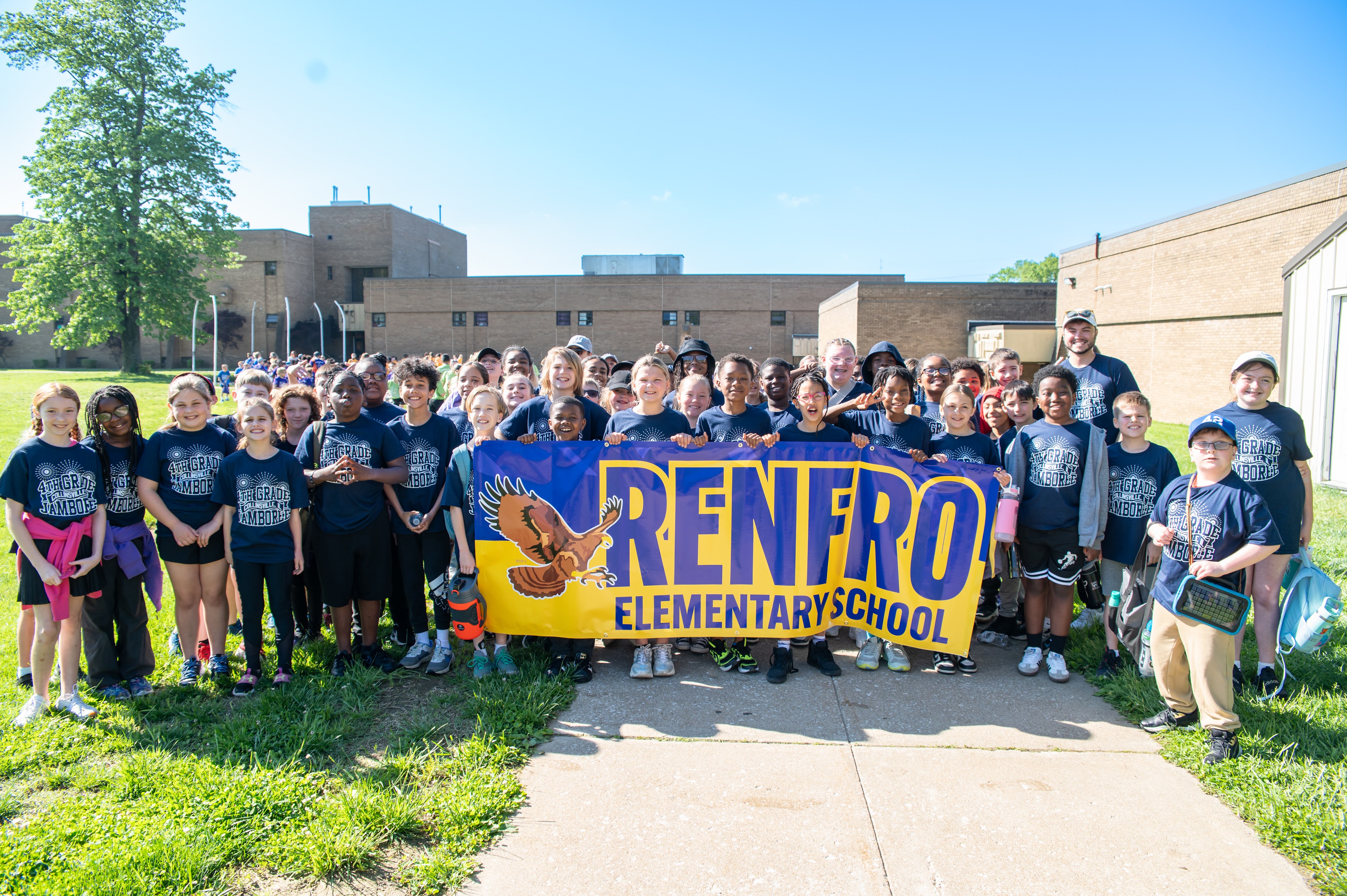 A group of students from Renfro Elementary School pose for a photo, holding a banner with the school's name and a flying eagle.