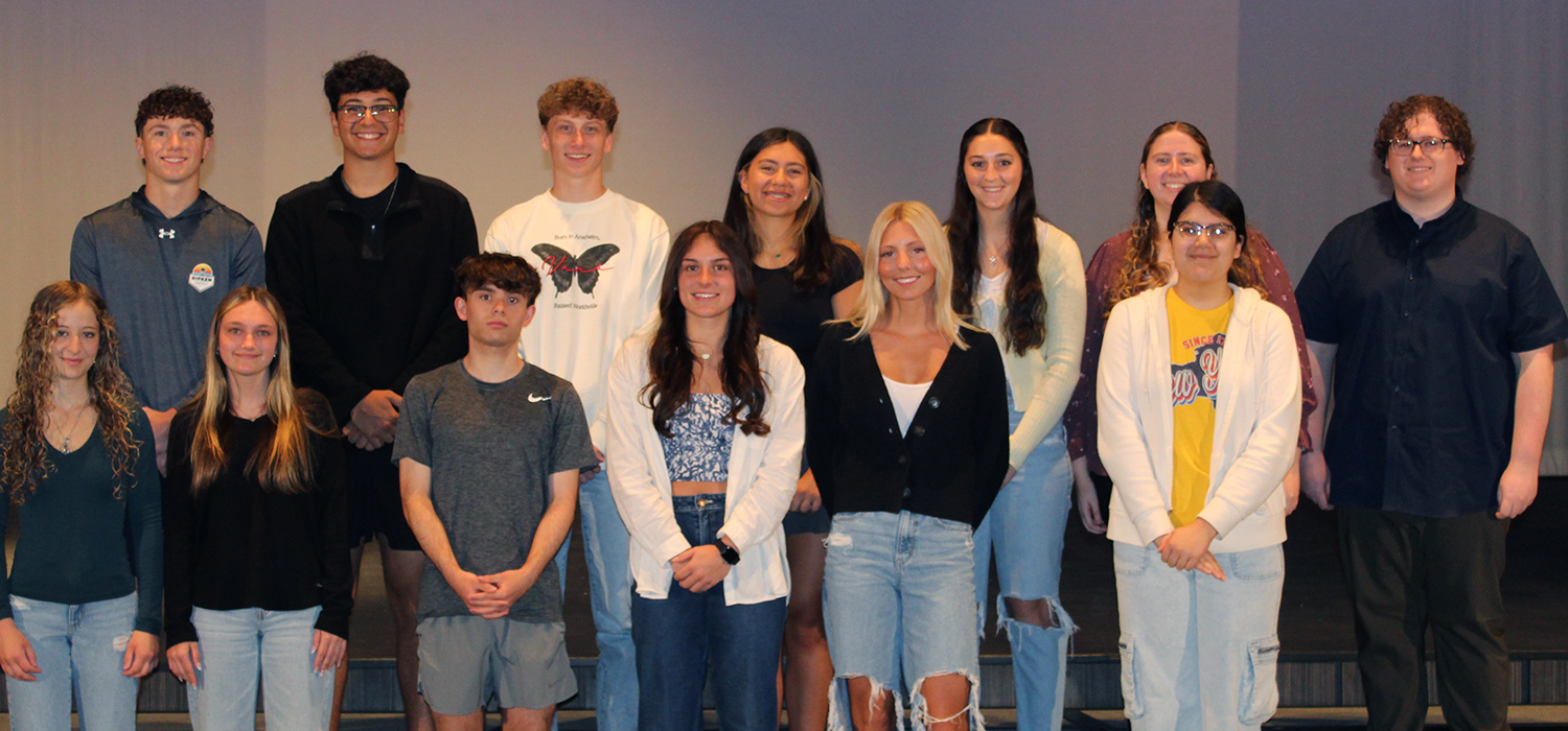 A group of diverse young adults pose together, smiling for the camera.