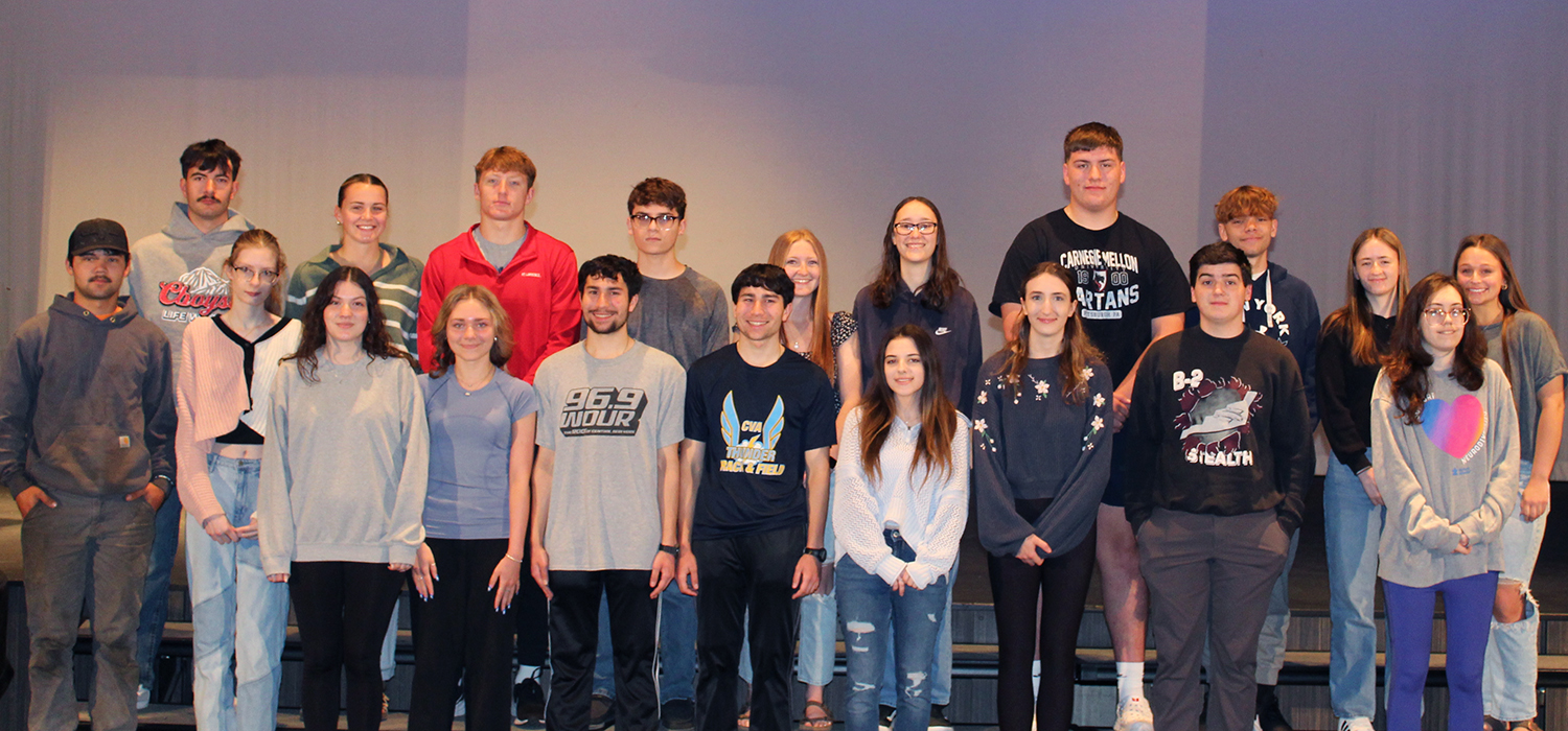 A group of diverse young adults stand together, posing for a photo.
