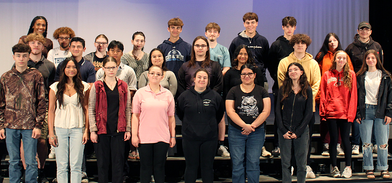 A group of diverse young adults pose together, smiling for the camera.