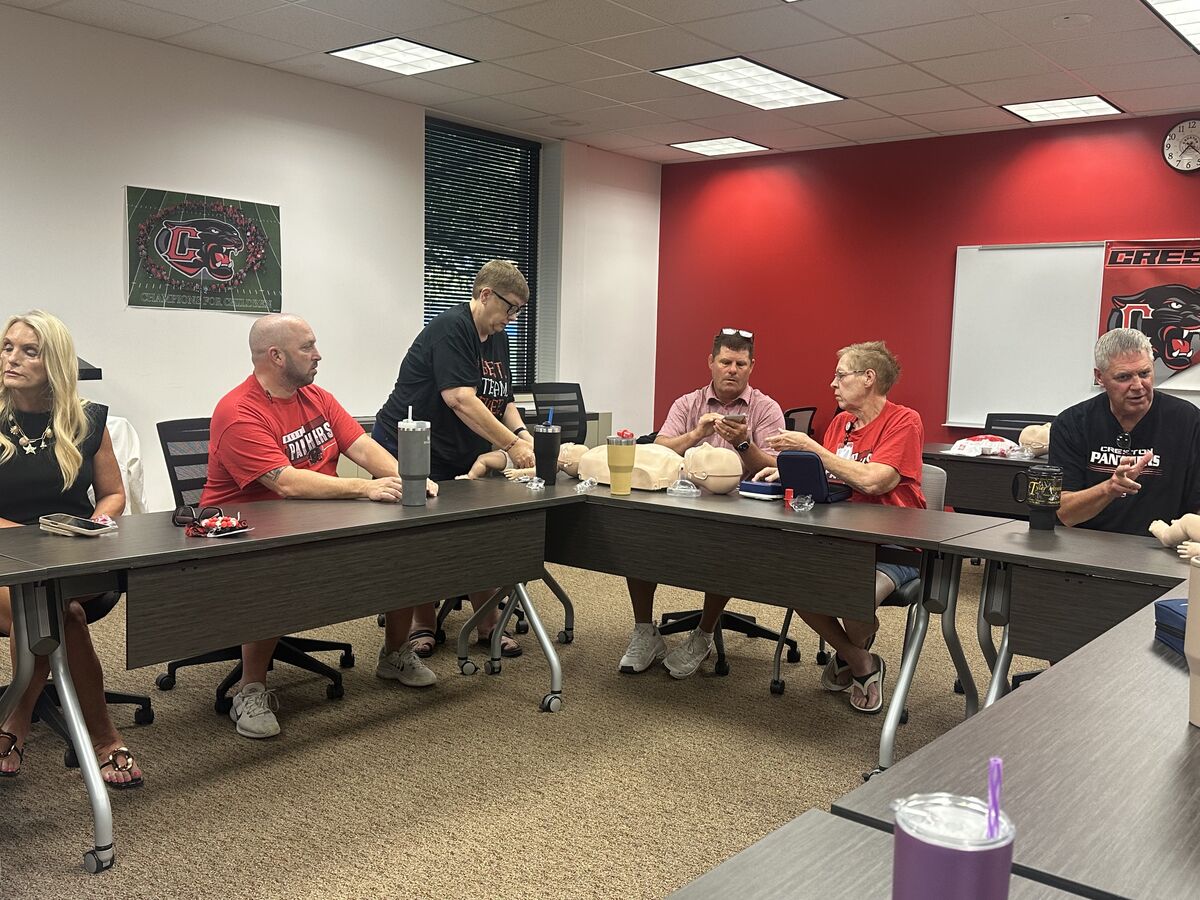 A group of people participate in a first aid training session in a classroom.