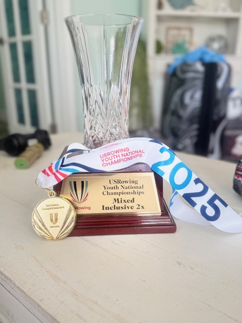 A gold medal and trophy from the USRowing Youth National Championships sit on a table.