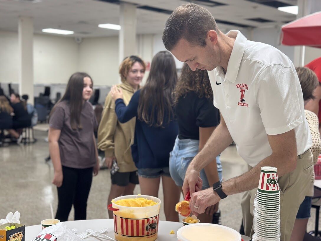 A man scoops ice cream for a group of people at an event.