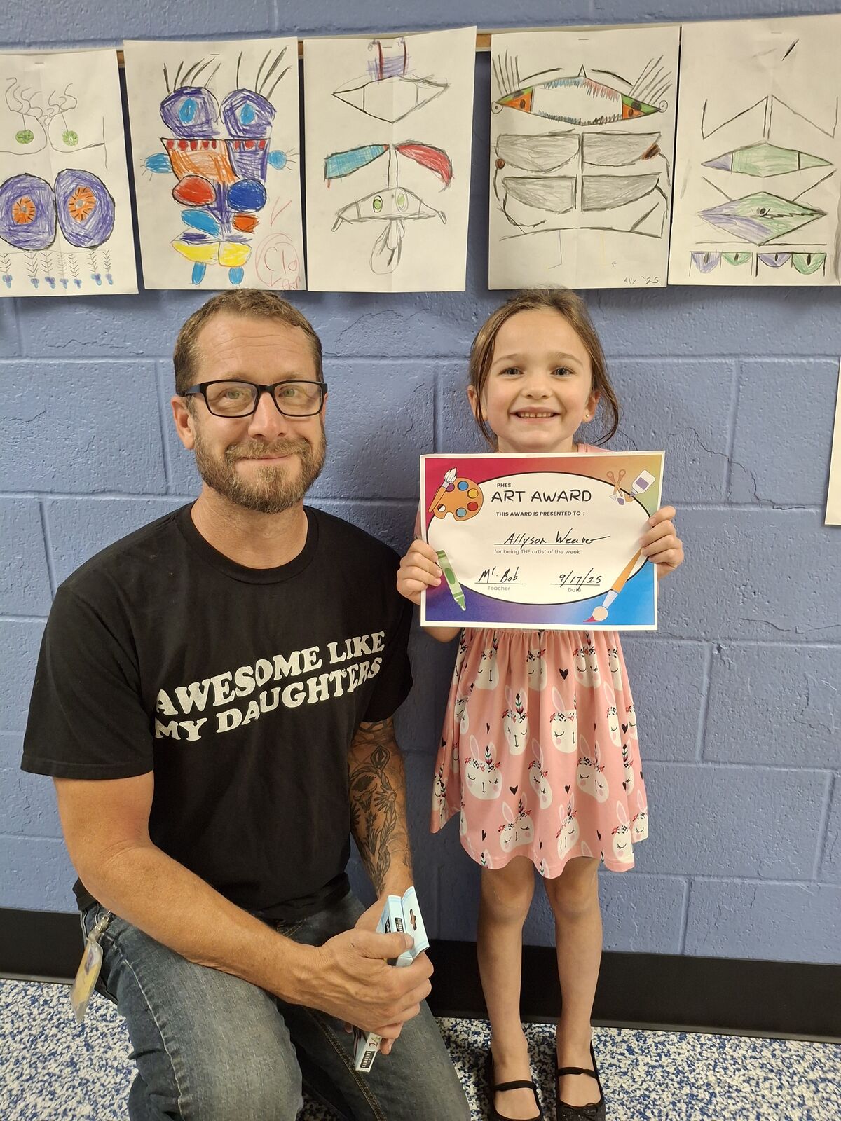 A young girll smiles, holding an art award