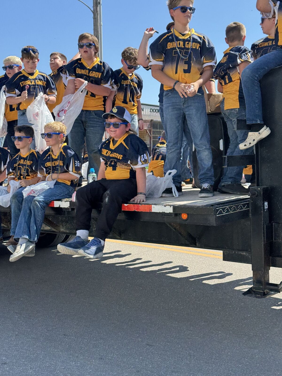 A group of people in matching jerseys stand on the back of a truck.