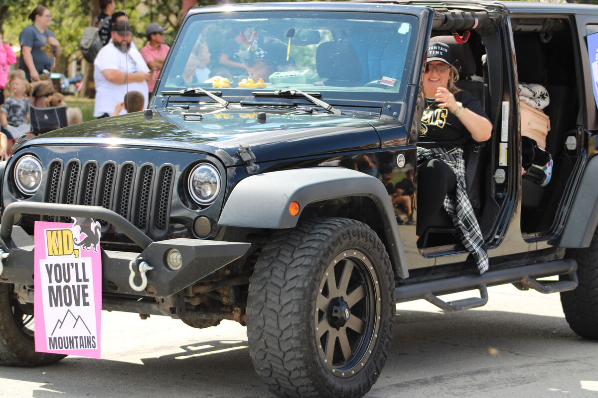 A black Jeep with a smiling CIS librarian in the driver's seat during Homecoming parade