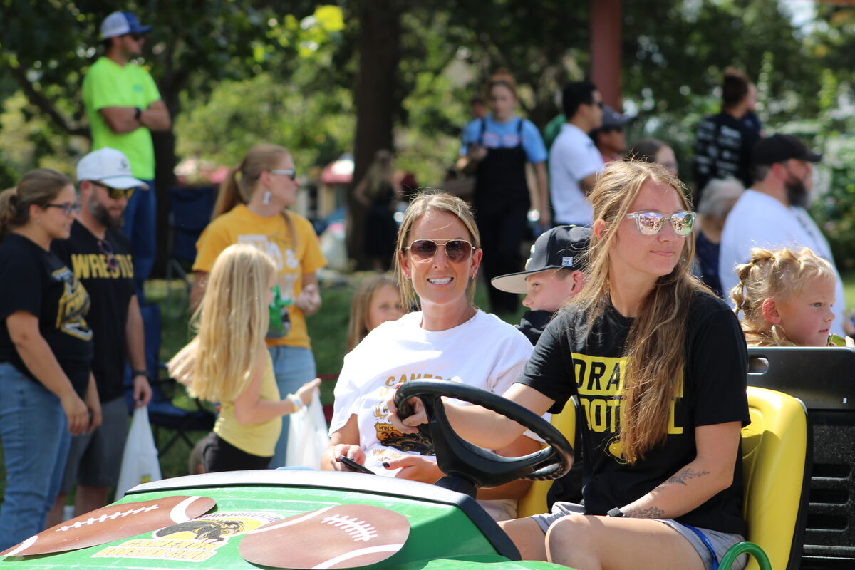 Athletic department staff in a green utility vehicle smile