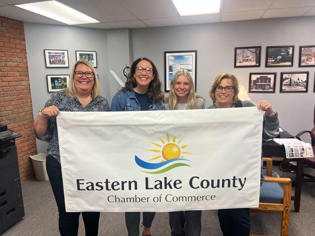 Four people hold a banner for the Eastern Lake County Chamber of Commerce.