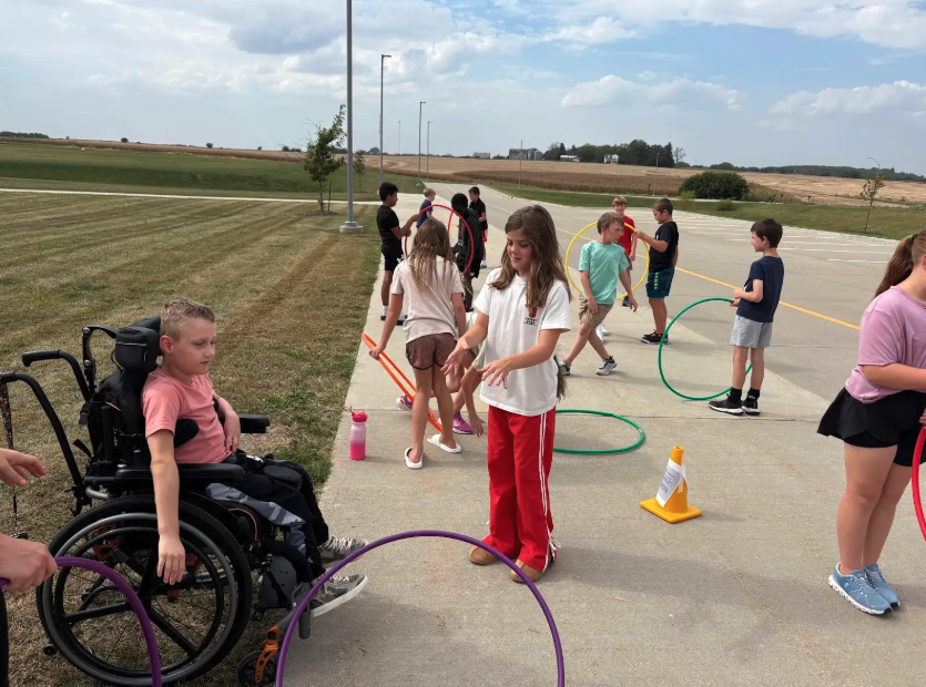 Children play with hula hoops outdoors on a sunny day.