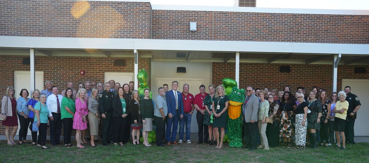 A large group of people pose for a photo in front of a brick building.