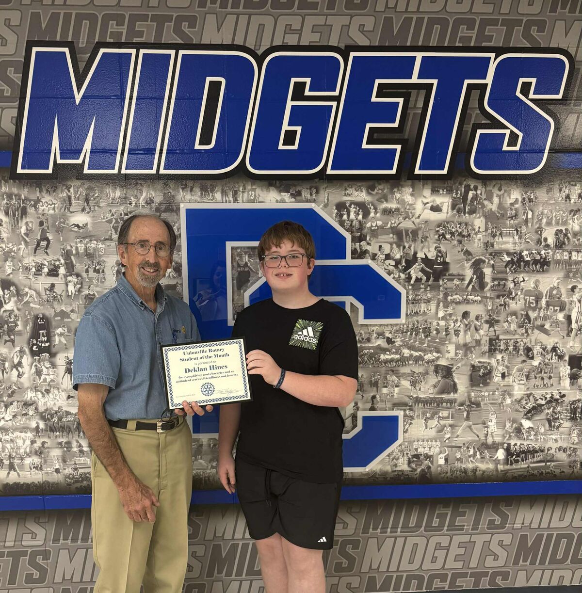 rotary student of the month holding certificate in front of wall