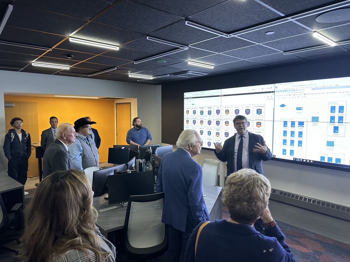 A presentation is given in a modern office setting, with a large screen displaying data.