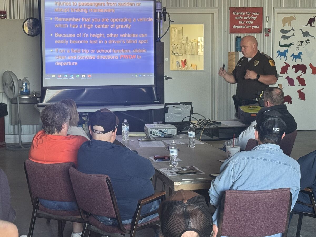 A law enforcement officer gives a presentation to a group of people seated at a table.