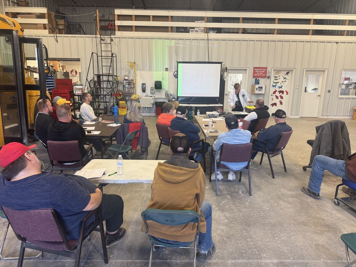A group of people attend a training session in a large workshop setting.