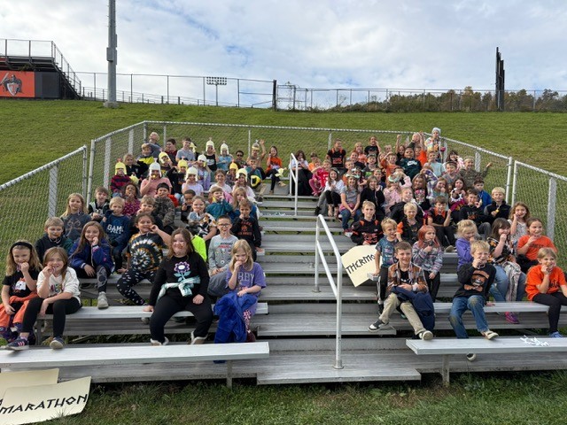 A large group of children pose on bleachers, smiling for the camera.