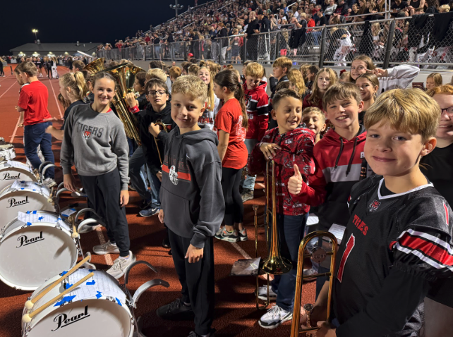 A group of young musicians pose for a photo on a football field.