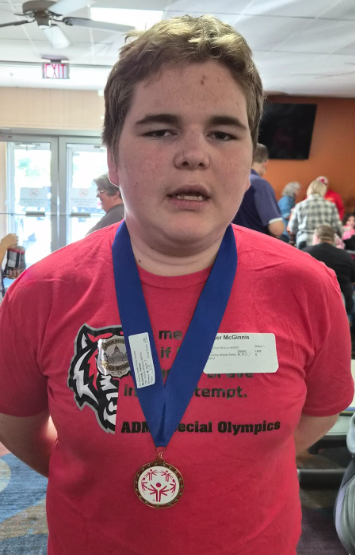 A young man wearing a medal and a red shirt with a tiger logo.