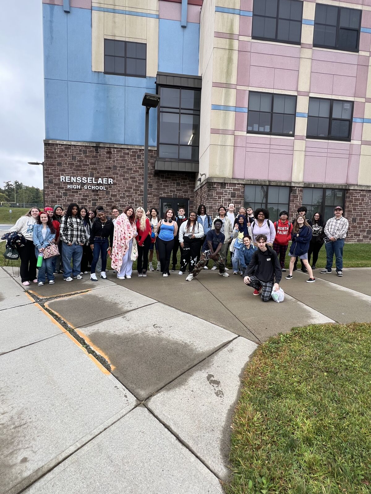 A group of students stand outside Rensselaer High School, posing for a photo.