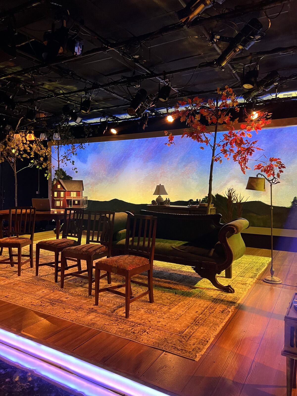 A stage set with a painted backdrop of a landscape and seating.