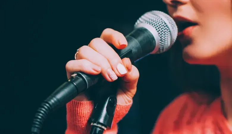 A person holds a microphone, ready to sing or speak.