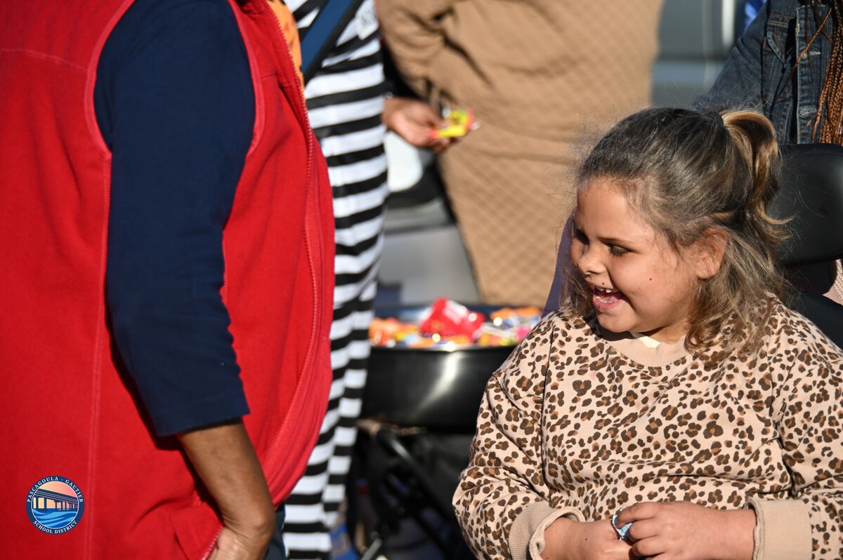 A young girl smiles, looking at something off-camera, with a leopard print shirt.