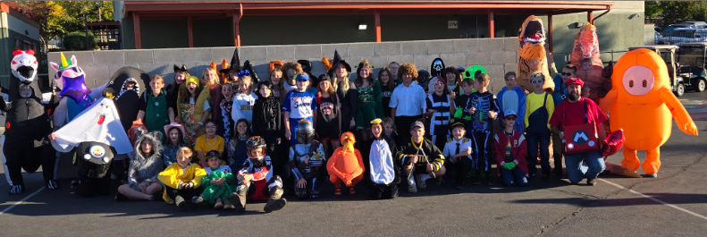 A large group of people in various costumes pose for a photo outdoors.