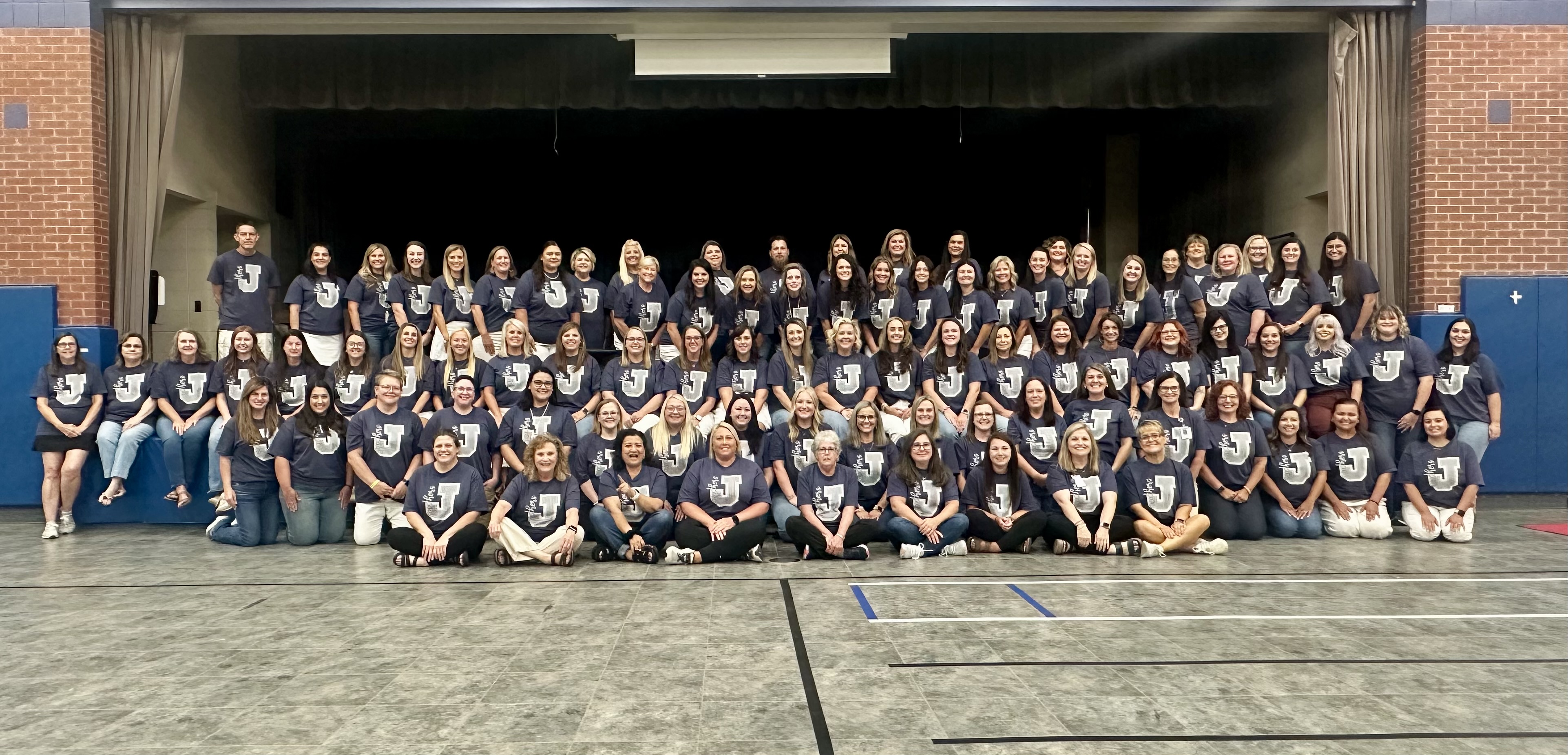 A large group of people wearing matching shirts pose for a photo.
