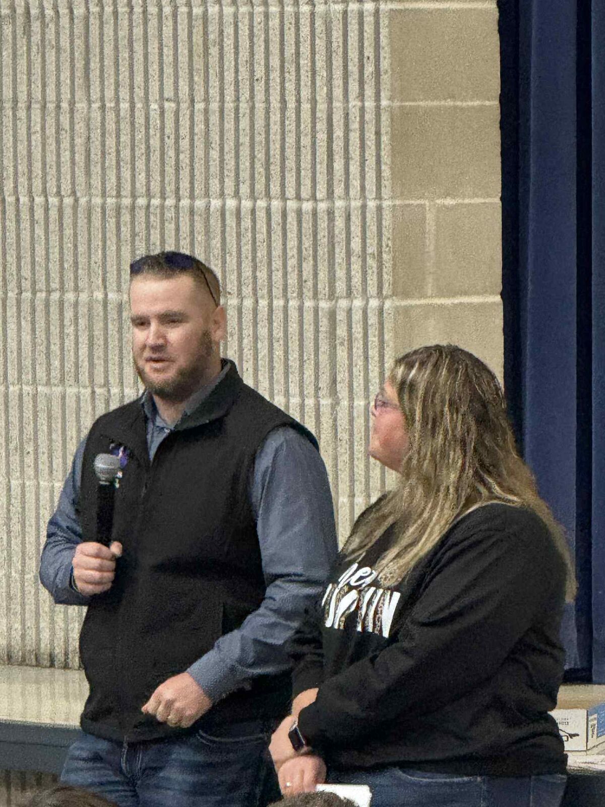 shawn gott speaks in the mic while jill payne listens