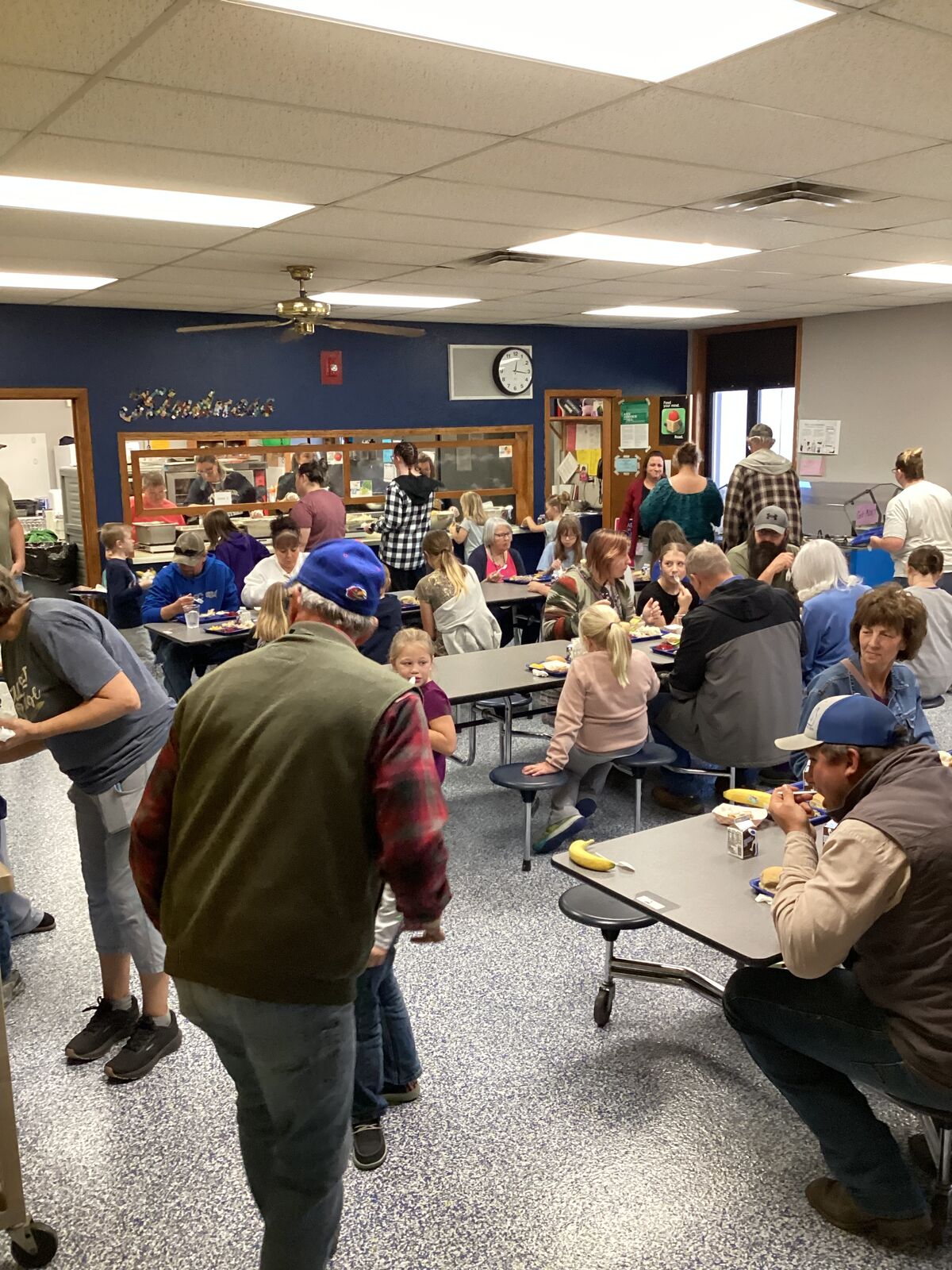A group of people are gathered at tables in a brightly lit room.