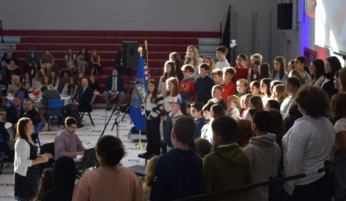 A large group of people, including children, gather indoors for an event.