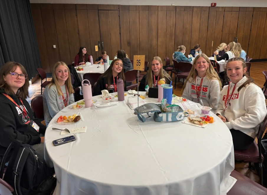 A group of young people sit around a table, enjoying a meal.