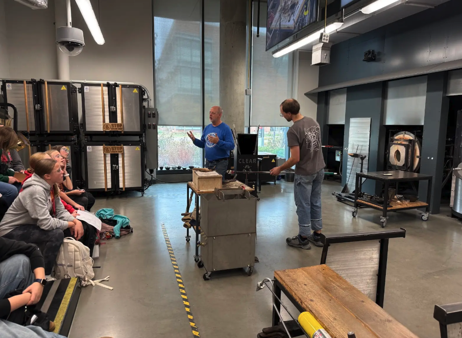 A glassblowing demonstration takes place in a workshop setting.