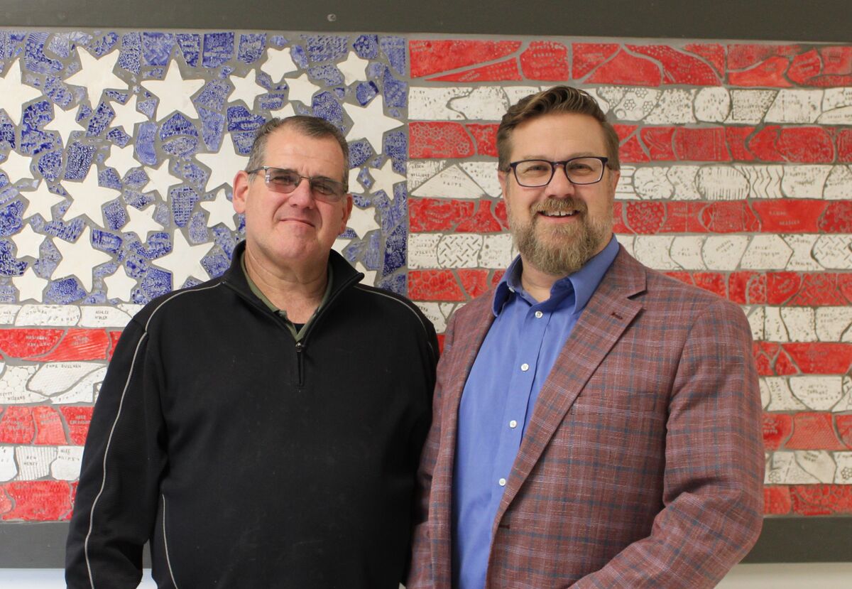 Dr. Robinson and Mr. Mackey pictured in front of a flag mosaic at CVMS