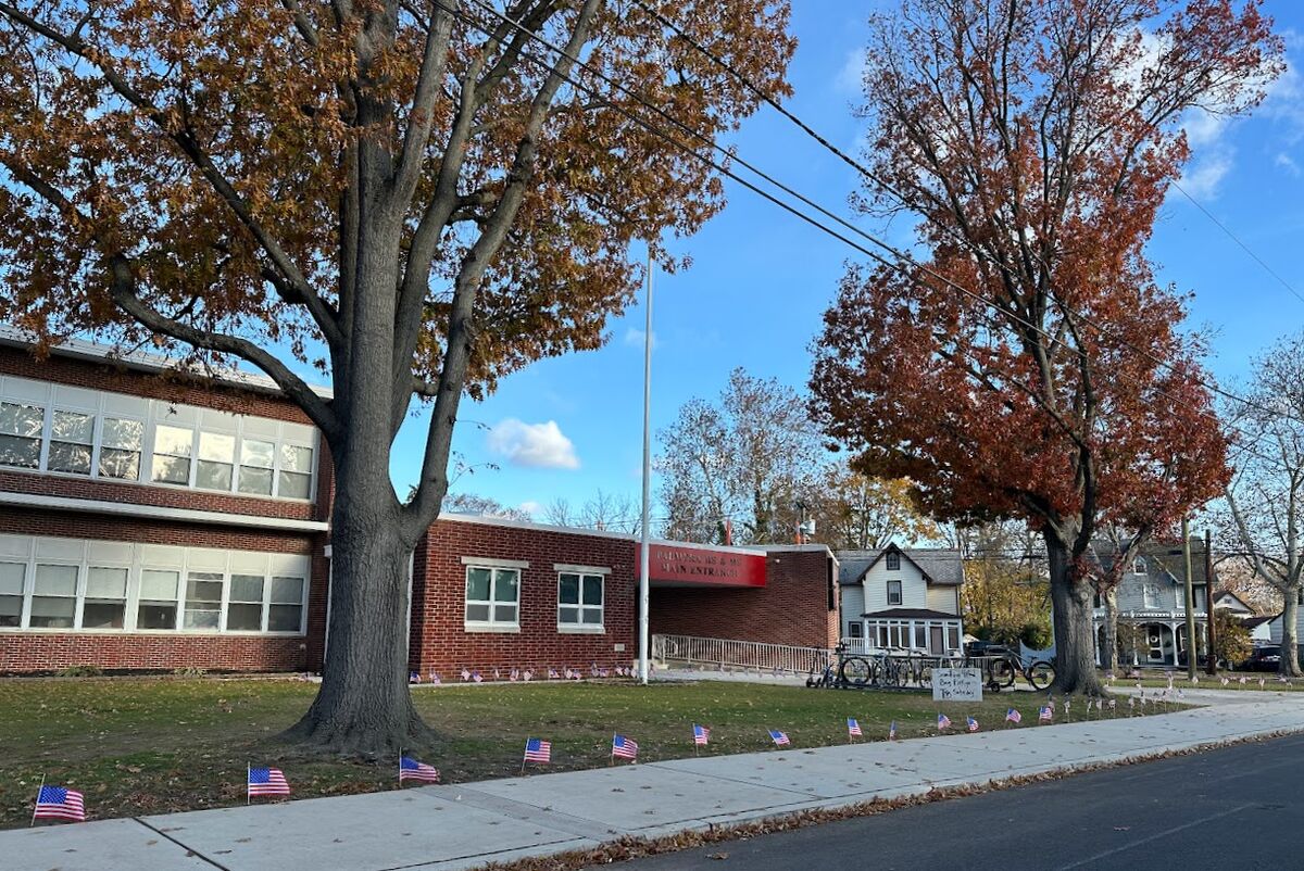 A brick school building with American flags lining the sidewalk.