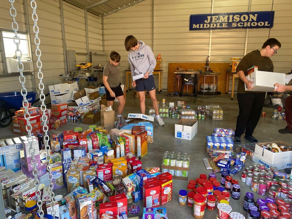 Volunteers sort and organize food items in a large storage space.