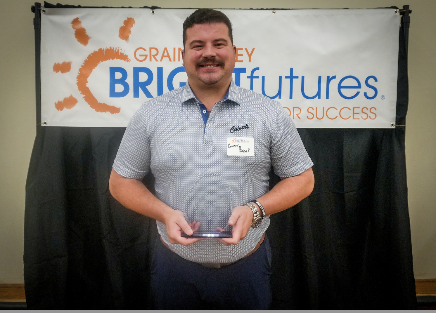 One individual holding an award in front of a banner that reads "Grain Valley Bright Futures". 
