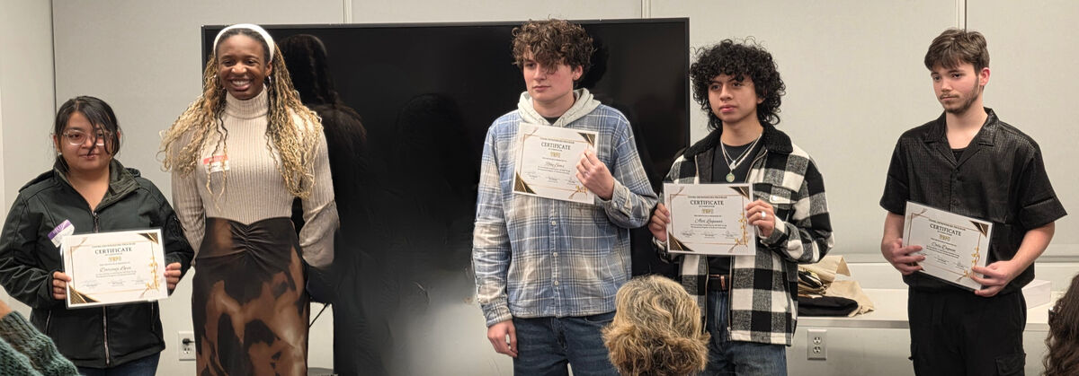 A group of young people hold certificates, smiling for the camera.