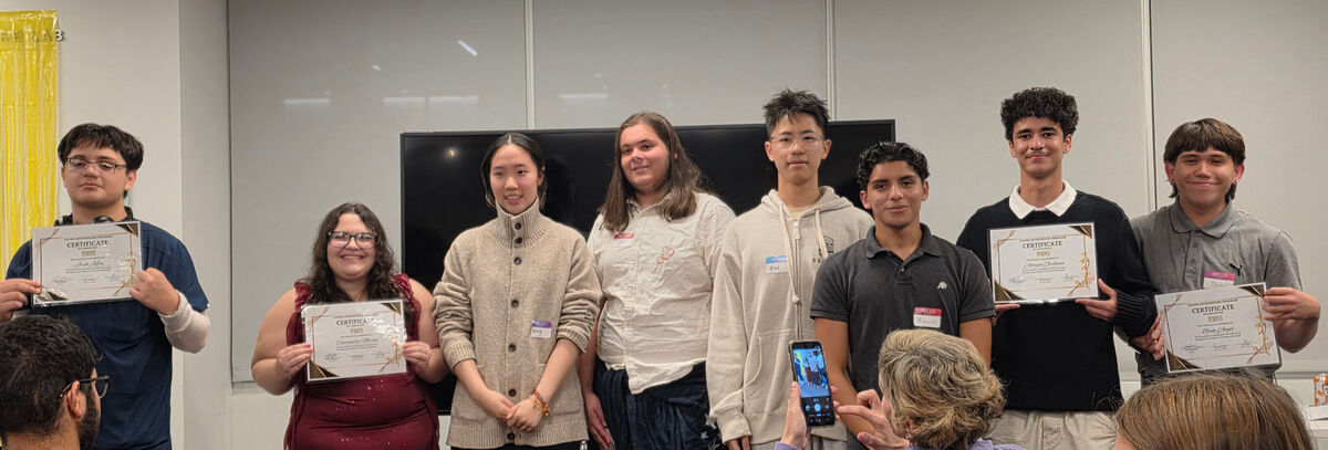 A group of young people stand together, holding certificates, smiling for a photo.