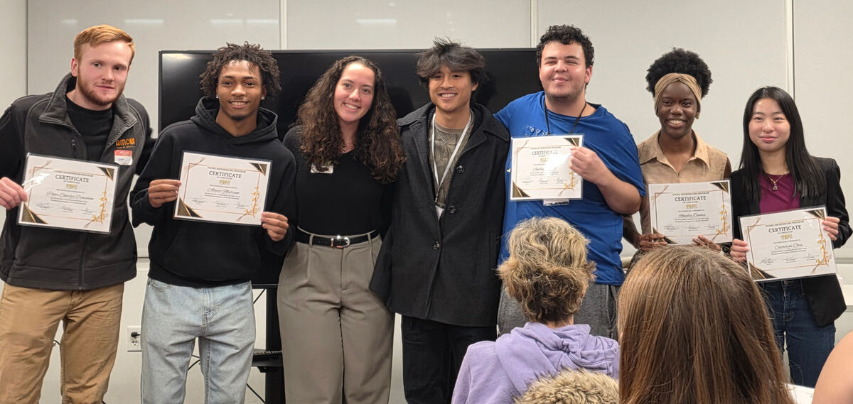 A group of diverse young people hold certificates, smiling for the camera.