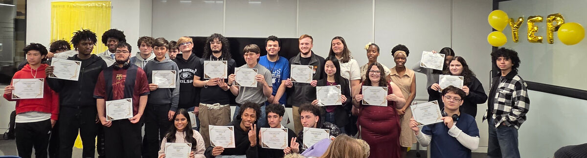 A diverse group of people hold certificates, smiling for a group photo.
